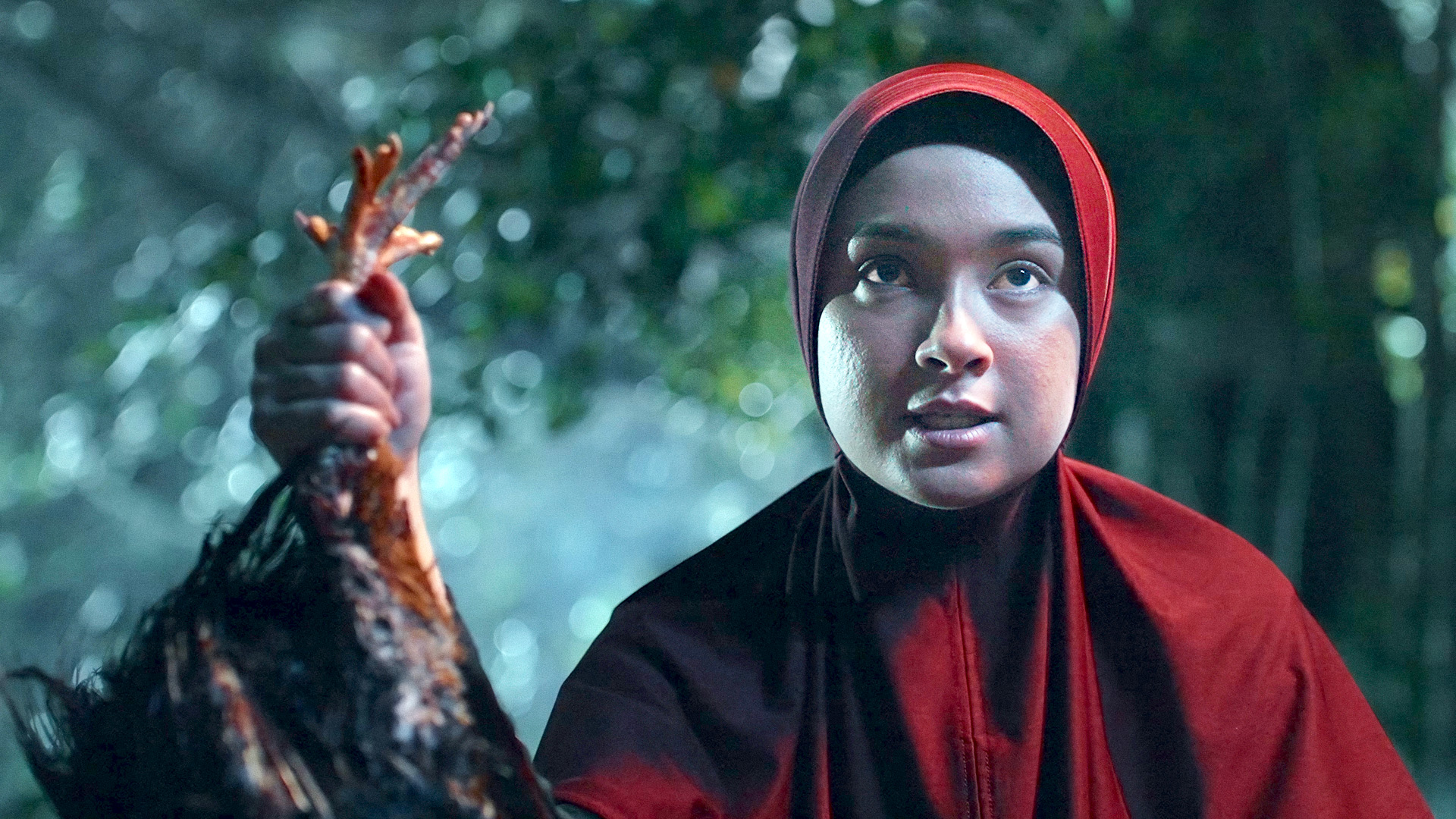 Caitlin Halderman as Riska wearing red hijab, holding a dead chicken the-hidden-hand-ep-7-highlight image 