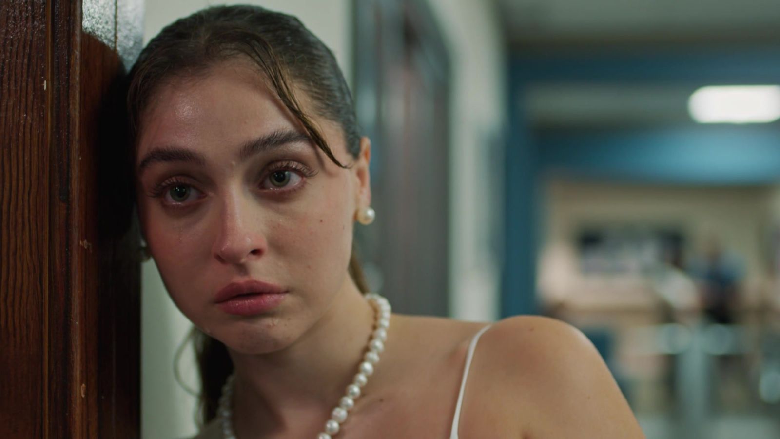 Cemre Baysel as a terrified Zeynep Candan with her head resting on a door frame in Sins and Roses Season 2 (Güller ve Günahlar / Woroud Wa Thonoub).